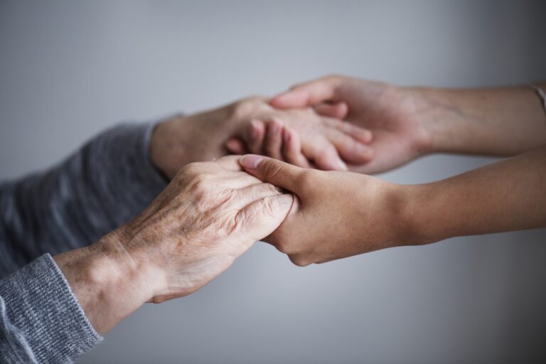 caregiver holds hands of older adult