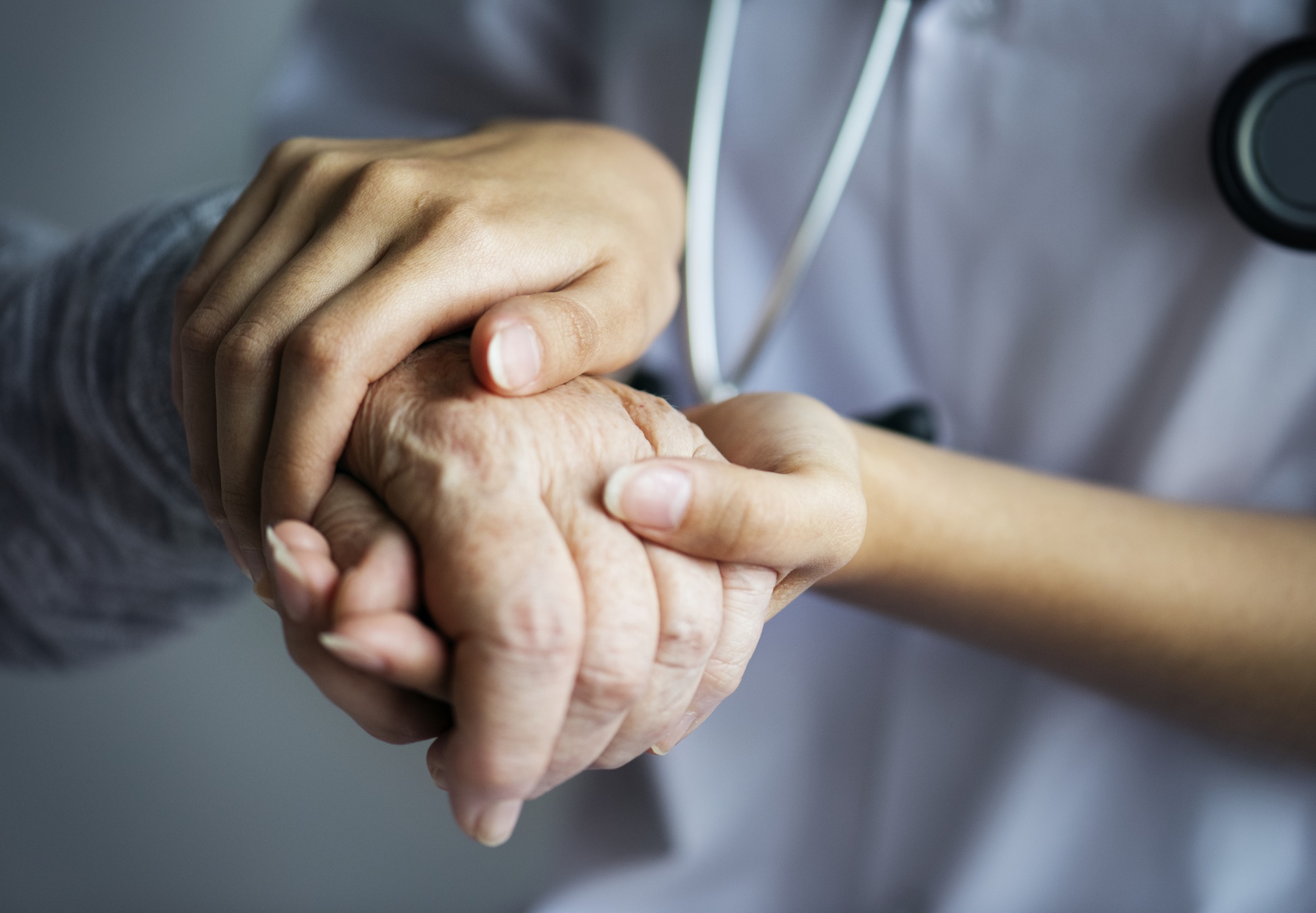CNA hands hold older adult's hand in a nursing home